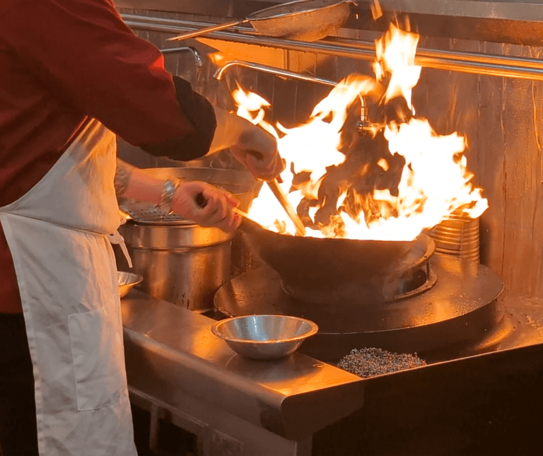 Chinese food being cooked in traditional woks
